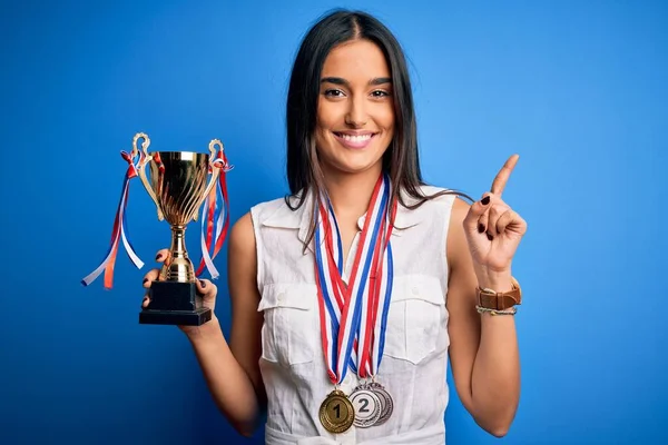 Joven Hermosa Morena Exitosa Mujer Con Medallas Sosteniendo Trofeo Sorprendido — Foto de Stock