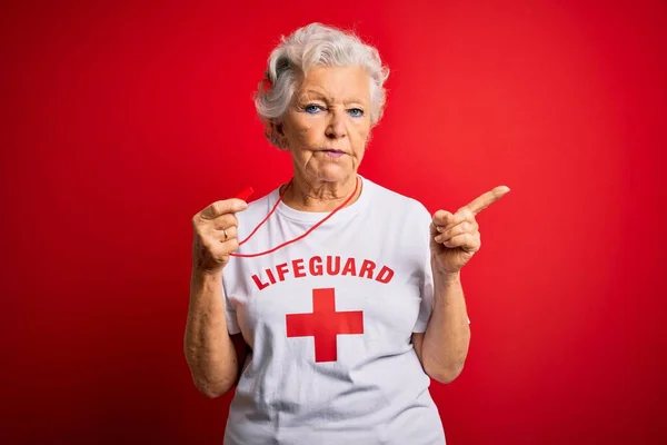 上了年纪的漂亮灰白头发的救生员 身穿印有红十字图案的T恤衫 手指头尖尖 侧面挂着广告 严肃而沉着 — 图库照片