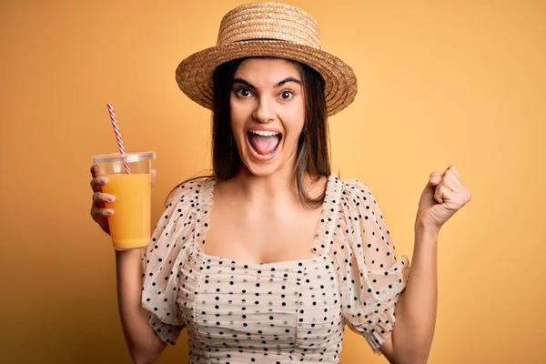 若いです美しいブルネット女性上の休暇を着て夏の帽子を飲むオレンジジュース悲鳴誇りと勝利と成功を祝う非常に興奮し 応援感情 — ストック写真