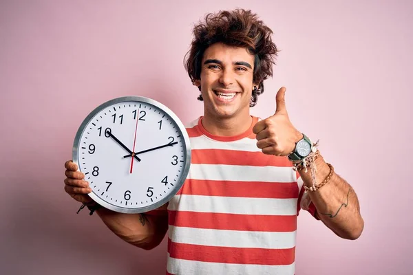 Joven Hombre Guapo Sosteniendo Gran Reloj Pie Sobre Fondo Rosa — Foto de Stock