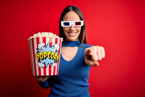 年轻的金发女人戴着3D眼镜 一边吃着爆米花一边看电影 一边用手指指着你和摄像机 面带微笑 面带微笑 — 图库照片