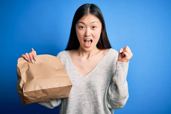 Młoda Azjatycka Kobieta Trzyma Torbę Wynos Jedzenie Niebieskim Odizolowanym Tle — Zdjęcie stockowe