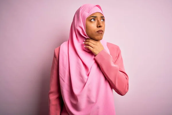 若いですアフリカ系アメリカ人女性身に着けていますムスリムヒジャーブ上の隔離されたピンクの背景に触れ痛みを伴う首 インフルエンザのための喉の痛み 雲と感染 — ストック写真