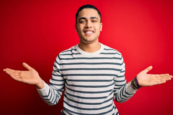 Jovem Brasileiro Vestindo Camiseta Listrada Casual Sobre Fundo Vermelho Isolado — Fotografia de Stock