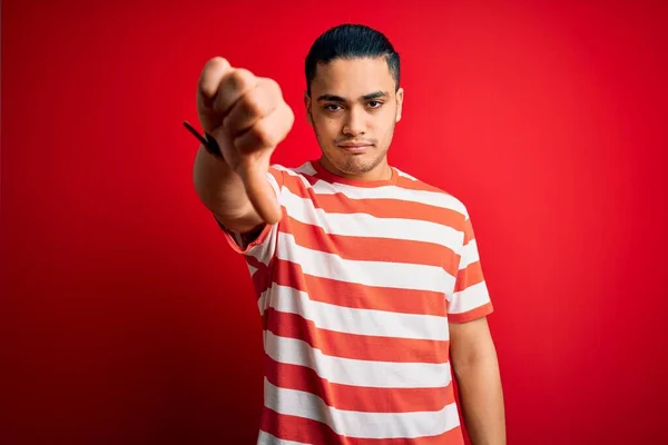 Jovem Brasileiro Vestindo Camiseta Listrada Casual Sobre Fundo Vermelho Isolado — Fotografia de Stock