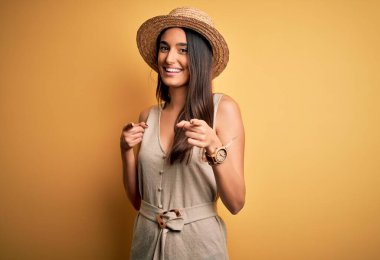 Genç ve güzel esmer kadın tatilde. Sıradan elbiseler ve şapkalar giyip kamerayı mutlu ve komik yüzüyle işaret ediyor. İyi enerji ve titreşimler.