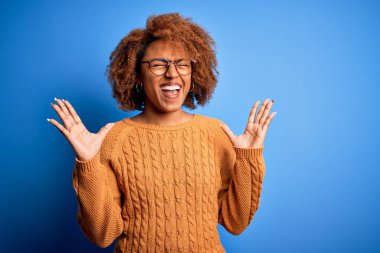 Kıvırcık saçlı, genç, Afro-Amerikan bir kadın çılgın ve çılgın başarısını kutluyor. Kolları havada ve gözleri kapalı, heyecanlı bir şekilde çığlık atıyor. Kazanan konsept