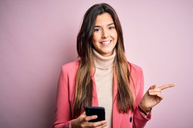 Genç ve güzel bir kız beyaz arka plan üzerinde akıllı telefon kullanarak konuşuyor. Çok mutlu bir şekilde el ve parmak kenarı işaret ediyor.