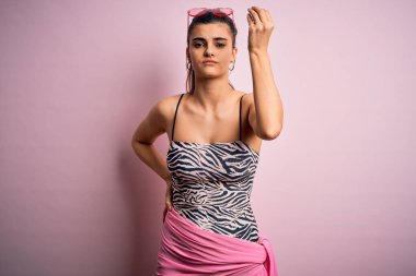 Genç, güzel, esmer, tatilde. Pembe arka planda mayo giyiyor. İtalyan jestleri yapıyor.