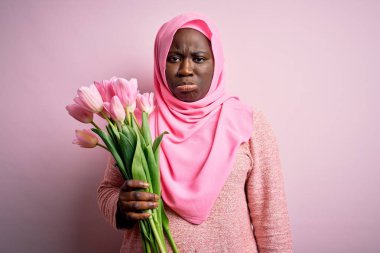 Genç Afro-Amerikan artı cüsseli kadın elinde pembe laleler buketi tutuyordu. Depresyondaydı ve üzüntüden ağlıyordu. Kızgın ve korkmuştu. Üzücü ifade.