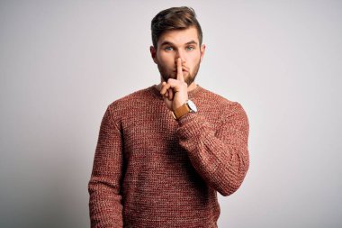 Sakallı, mavi gözlü, beyaz arka planda sıradan bir süveter giyen genç sarışın adam sessiz olup dudaklarını öpmek istiyor. Sessizlik ve gizli konsept.