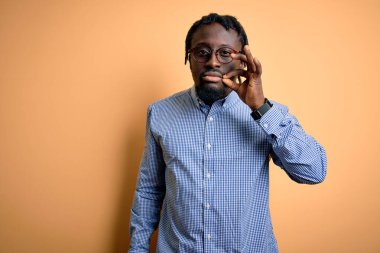 Sarı arka planın üzerine gömlek ve gözlük takan yakışıklı Afro-Amerikan bir adam. Ağzı ve dudakları parmakları fermuar gibi kapalı. Gizli ve sessiz, tabu konuşması