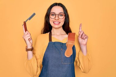 Sarı arka plan üzerinde jilet tutan önlük giyen genç ve güzel bir berber kadın bir fikir ya da soru işareti ile şaşırdı.