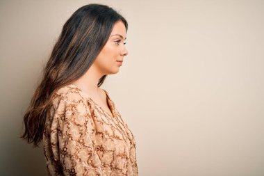 Genç, güzel, esmer bir kadın. Günlük tişört giyiyor. Beyaz arka plan üzerinde duruyor..