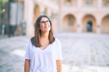 Mutlu ve kendinden emin gülümseyen genç ve güzel bir kadın. Kasaba caddesinde yüzünde gülümsemeyle dikilirken