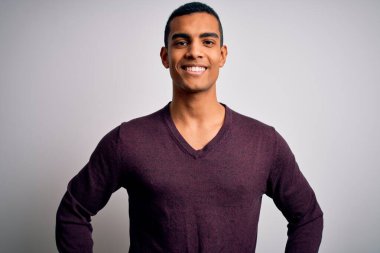 Genç, yakışıklı, Afro-Amerikan bir adam beyaz arka planda sıradan bir süveter giyiyor ve yüzünde mutlu ve havalı bir gülümseme var. Şanslı kişi..