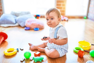 Anaokulunda bir sürü oyuncakla oynayan sevimli bir çocuk.