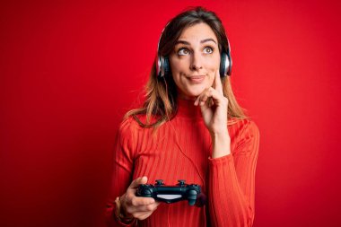 Genç ve güzel esmer kadın video oyunu oynuyor. Neşeli ve kulaklık kullanıyor. Ciddi yüz ifadeleri var.