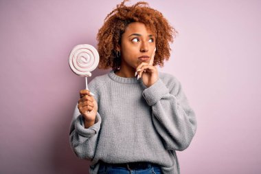 Kıvırcık saçlı, tatlı şekerlemeler yiyen, soru soran, kafası karışık, güzel Afro-Amerikan bir kadın.