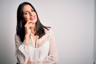 Mavi gözlü genç esmer kadın izole edilmiş beyaz arka plan üzerine günlük tişört giyiyor kameraya bakıyor kollarını kavuşturup gülümsüyor ve çenesini kaldırıyor. Olumlu düşünüyorum..