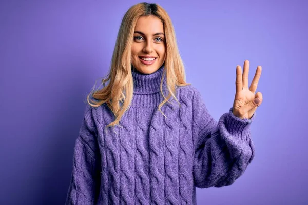 若いです美しいですブロンド女性身に着けていますカジュアルTurtleeckセーター上の紫背景ショーと指摘しますとともに指数3自信と幸せ — ストック写真