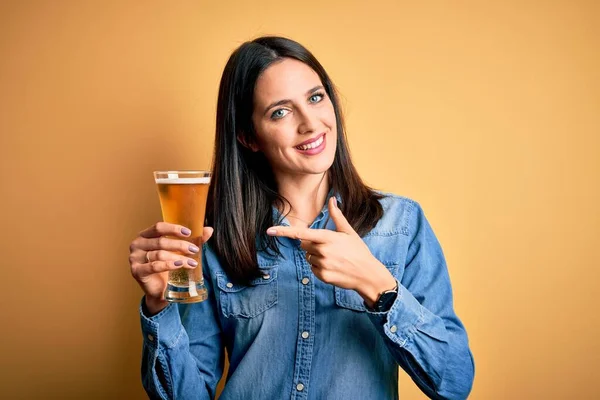 여자가 맥주를 마시고 있습니다 손가락으로 행복하게 가리키고 — 스톡 사진