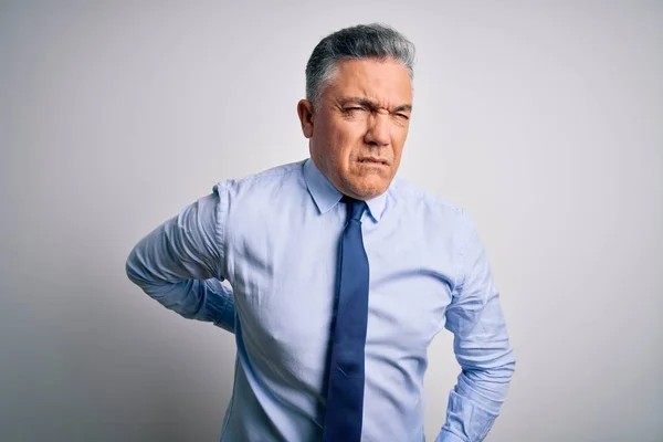 Middle age handsome grey-haired business man wearing elegant shirt and tie Suffering of backache, touching back with hand, muscular pain