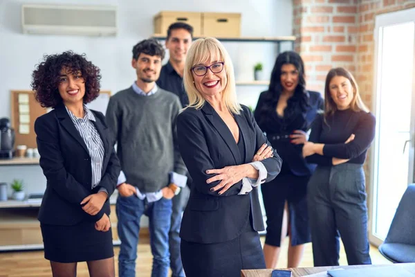 Group of business workers smiling happy and confident. Posing together with smile on face looking at the camera, middle age beautiful woman with crossed arms at the office