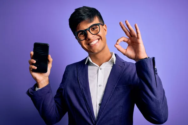 Mladý Pohledný Obchodník Bundě Brýlích Drží Smartphone Ukazující Obrazovku Dělá — Stock fotografie