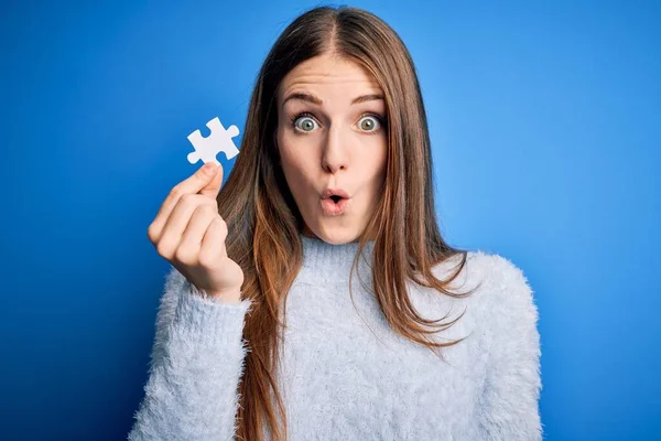 Junge Schöne Rothaarige Frau Hält Puzzleteil Über Isoliertem Blauem Hintergrund — Stockfoto