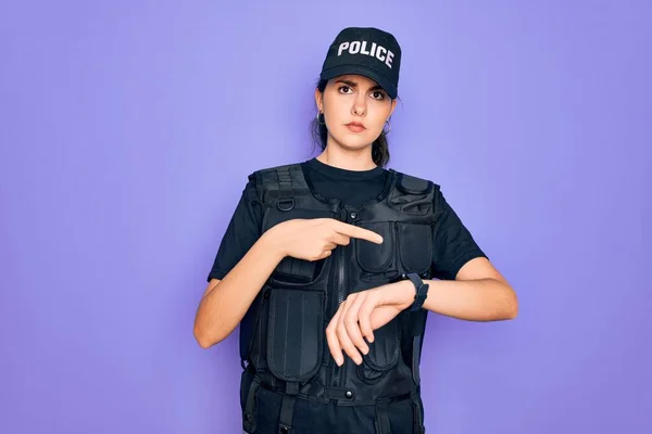Young police woman wearing security bulletproof vest uniform over purple background In hurry pointing to watch time, impatience, upset and angry for deadline delay