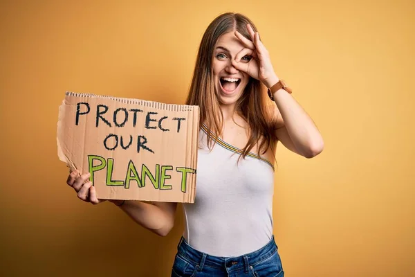 若いです赤毛の女性要求環境を保持するバナーで保護された惑星のメッセージで幸せな顔を笑顔で手でOkサインをします — ストック写真