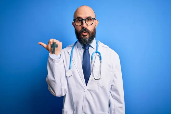 ハンサムなはげ医者男とともに髭を身に着けている眼鏡と聴診器上の青の背景驚くべきポインティングとともに手指で側面 口を開けてびっくり式 — ストック写真