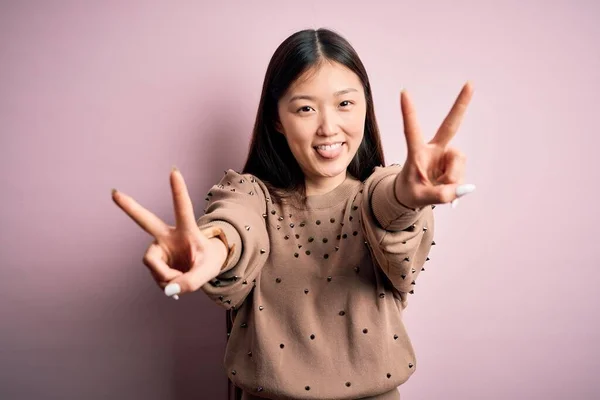 입고우아 스웨터를 아리따운 아시아 손가락으로 승리의 표시를 웃음을 — 스톡 사진