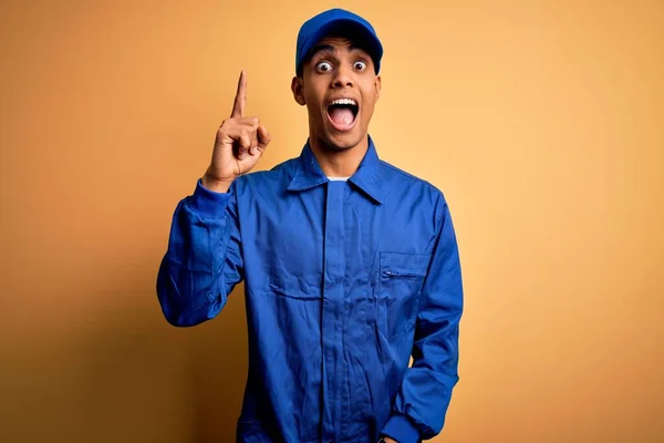 Jonge Afro Amerikaanse Monteur Blauw Uniform Pet Gele Achtergrond Wijzend — Stockfoto