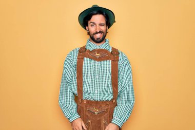 Almanya festivali için geleneksel Alman Ekim Festivali kıyafeti giyen genç yakışıklı adam kameraya seksi bir ifadeyle bakıyor, neşeli ve mutlu bir yüzle..