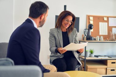 Mutlu ve kendinden emin gülümseyen iki orta yaşlı iş adamı. Ofiste evrakları tutarken gülümseme ile birlikte çalışmak.
