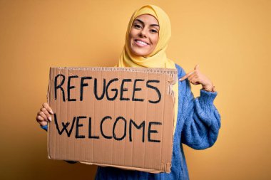 İslami tesettüre bürünmüş güzel bir Arap kadın elinde mültecilerle bayrak tutuyor. Sürpriz yüzlü, kendini gösteren bir mesaj.