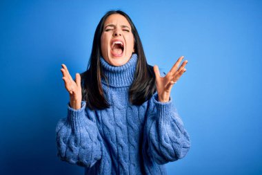 Mavi gözlü, balıkçı yaka kazak giyen genç esmer kadın başarı için deli ve çılgın bir kutlama yapıyor kolları havada ve gözleri kapalı heyecanla bağırıyor. Kazanan konsept