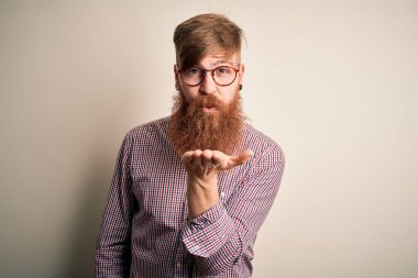 Yakışıklı, kızıl saçlı, sakallı, gözlüklü, izole bir arka planı olan yakışıklı bir iş adamı. Kameraya bakıp havada öpüşürken güzel ve seksi görünüyor. Aşk ifadesi.