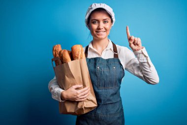 Mavi gözlü genç fırıncı kadın elinde ekmek torbasıyla bir fikir ya da soru işareti ile şaşırmış mutlu yüzlü, bir numara