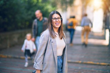 Mutlu ve kendinden emin gülümseyen genç ve güzel bir kadın. Kasaba caddesinde yüzünde gülümsemeyle dikilirken
