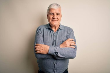 Üst düzey yakışıklı beyaz gömlekli adam izole edilmiş beyaz arka planda duruyor ve kollarını kavuşturup kameraya bakıyor. Pozitif kişi.