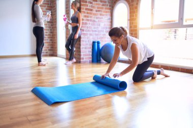 Spor salonunda yoga yapmak için spor minderi kullanan genç ve güzel bir sporcu.