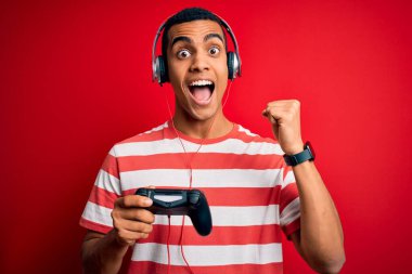 Yakışıklı afro-amerikan oyuncu video oyunu oynuyor jostick ve kulaklık kullanıyor gururla bağırıyor ve zaferi ve başarıyı kutluyor çok heyecanlı, coşkulu