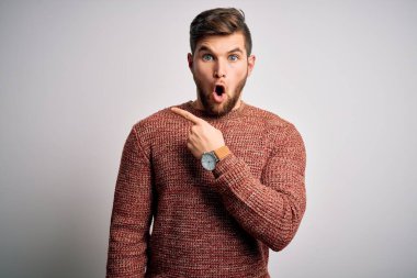 Sakallı ve mavi gözlü genç bir adam beyaz arka planda sıradan bir süveter giyiyor..