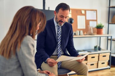 Mutlu ve kendinden emin gülümseyen iki orta yaşlı iş adamı. Ofiste evrakları tutarken gülümseme ile birlikte çalışmak.