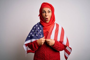 Orta yaşlı vatansever kadın geleneksel Müslüman başörtüsü takıyor. Elinde Birleşik Devletler bayrağı var. Şaşırmış bir yüzle korkmuş, korku ifadesinden korkmuş ve heyecanlanmış.