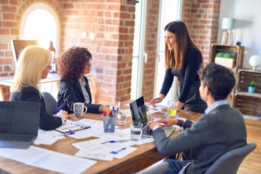 Bir grup iş adamı mutlu ve kendinden emin gülümsüyor. Yüzünde gülümsemeyle birlikte çalışmak. Genç ve güzel bir kadın büroda belgeleri açıklıyor.