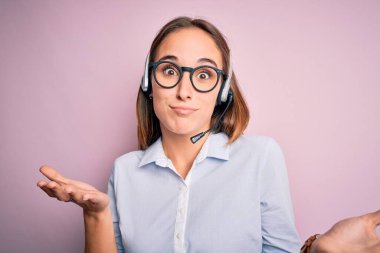 Genç, çağrı merkezi ajanı, gözlüklü, kulaklık takan, kafası karışmış, elleri ve kolları havada bir kadın. Şüphe kavramı.